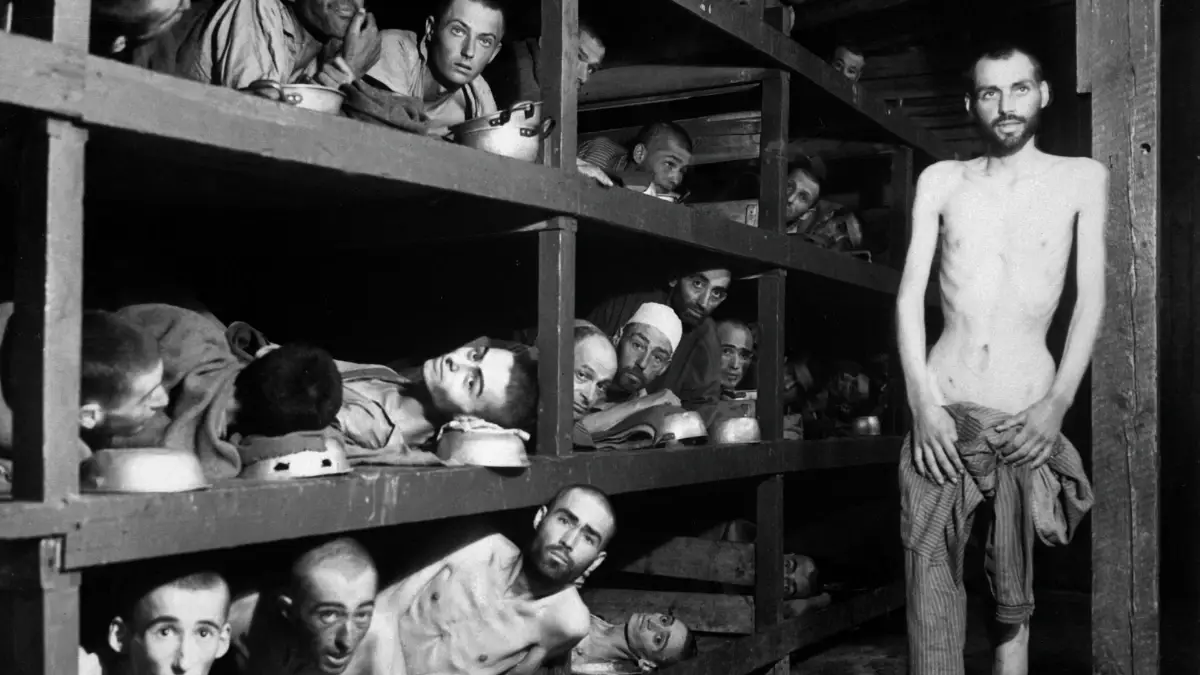 Black and white photograph of emaciated prisoners crowded into tiered wooden bunks inside Buchenwald concentration camp Barrack 56, photographed by the U.S. Army Signal Corps on April 16, 1945, five days after liberation.