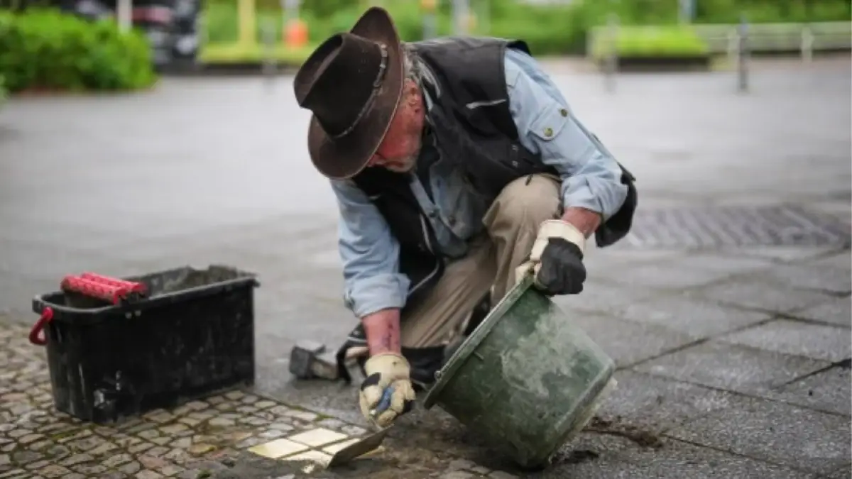 German artist Gunter Demnig installs Stolpersteine Holocaust memorial brass plaques Berlin.
